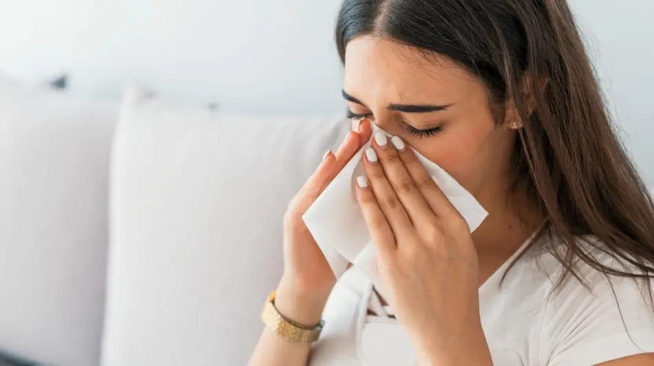 Kobieta wydmuchująca nos, objawy alergicznego nieżytu nosa lub zapalenia zatok