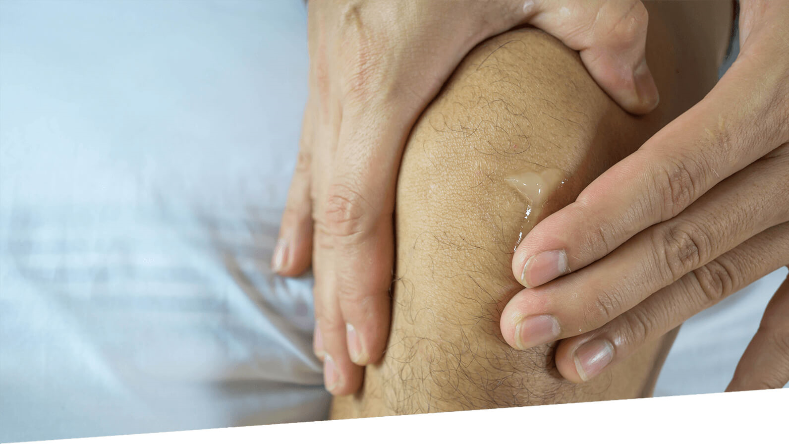 A person rubs cream into their knee.