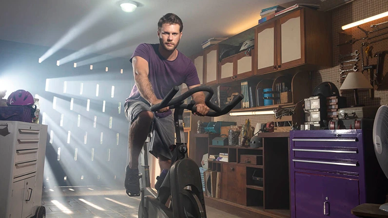 A man riding an exercise bike in his garage.