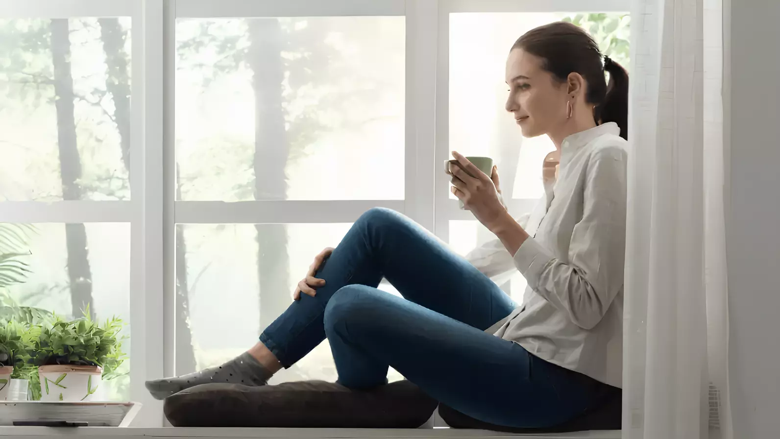 Seorang wanita duduk dengan nyaman di sofa sambil menikmati minuman.