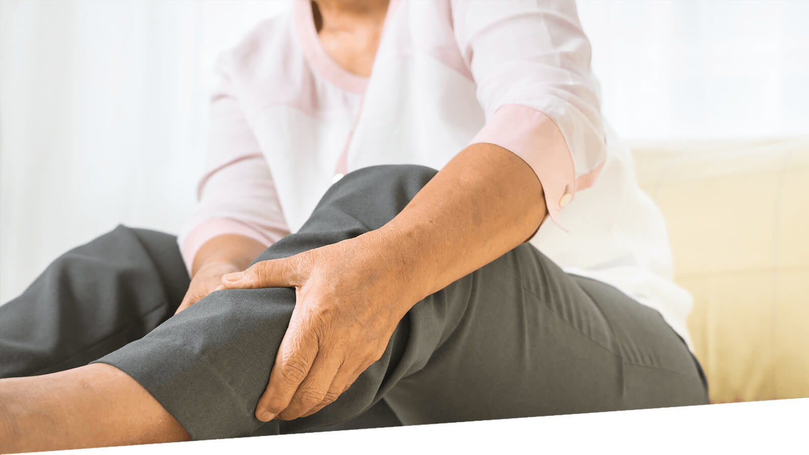 A woman grips her lower leg, appearing to be in pain.