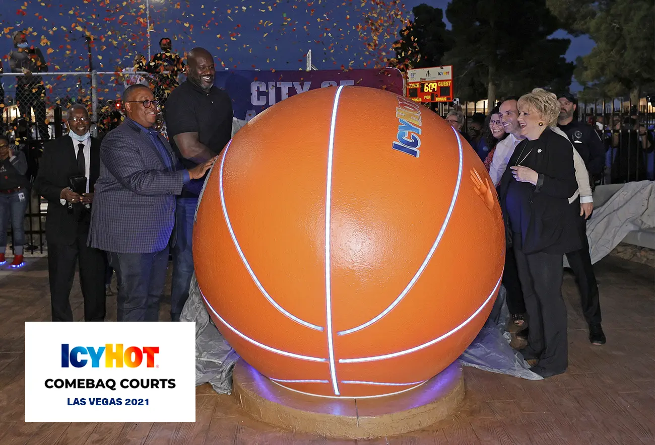 Shaquille O'Neal at the event on the newly renovated basketball court in Las Vegas, surrounded by several people, all gathered around a striking giant basketball figure adorned with the iconic Icy Hot logo on top.  The lower-left corner of the image features a label displaying the Icy Hot Comebaq Courts logo, along with the event's year (2021) and location (Las Vegas).