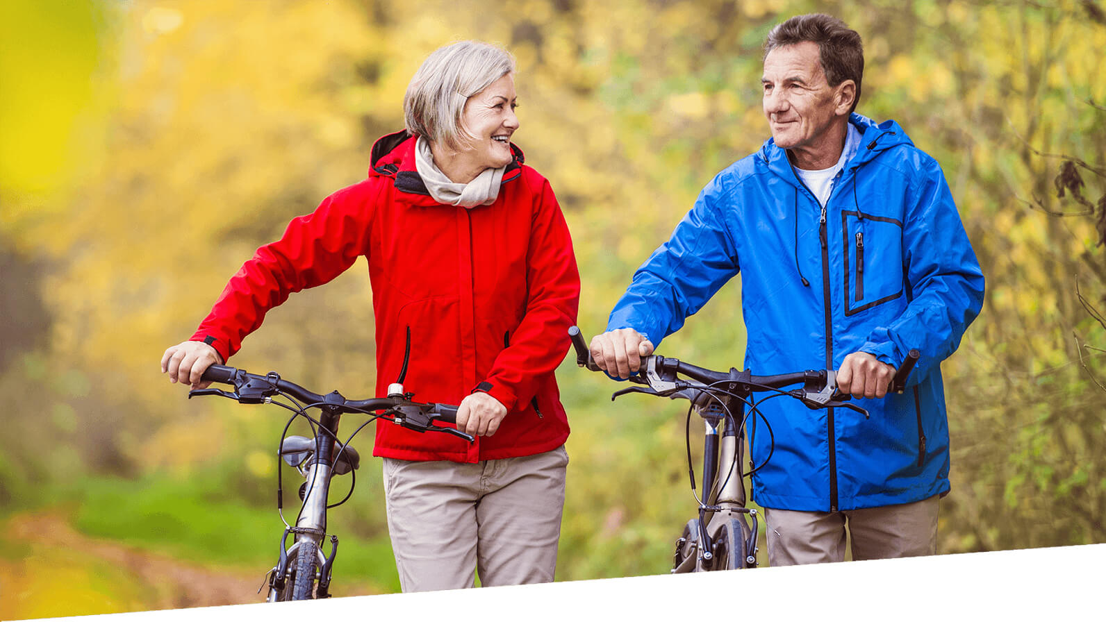 A couple enjoy time outdoors while walking their bicycles.