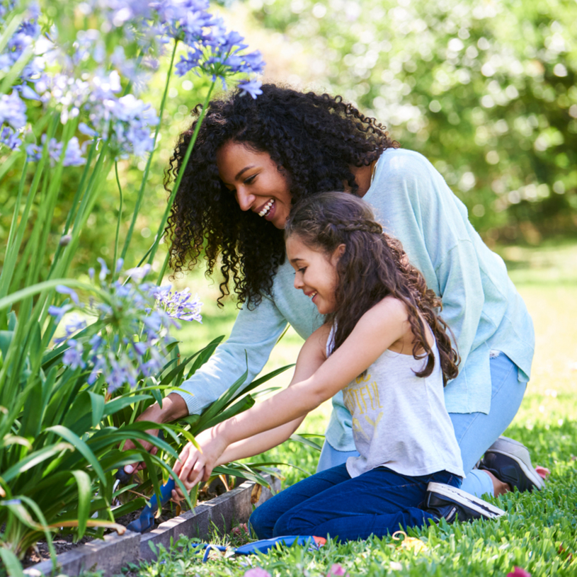 Mutter und Tochter pflanzen Blumen im Garten.